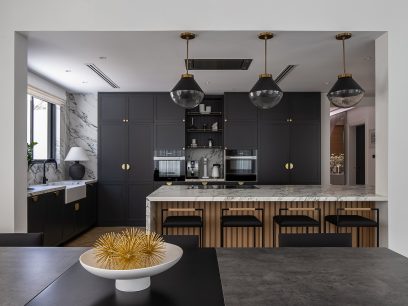 open-concept layout in the kitchen that has dark cabinetry with gold accents and an island